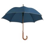 Dieser Holzregenschirm ist mit einem Reflektorband ausgestattet und zusätzlich individuell bedruckbar.
